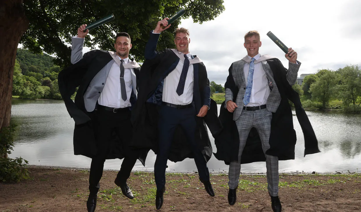 students with scrolls celebrating graduation