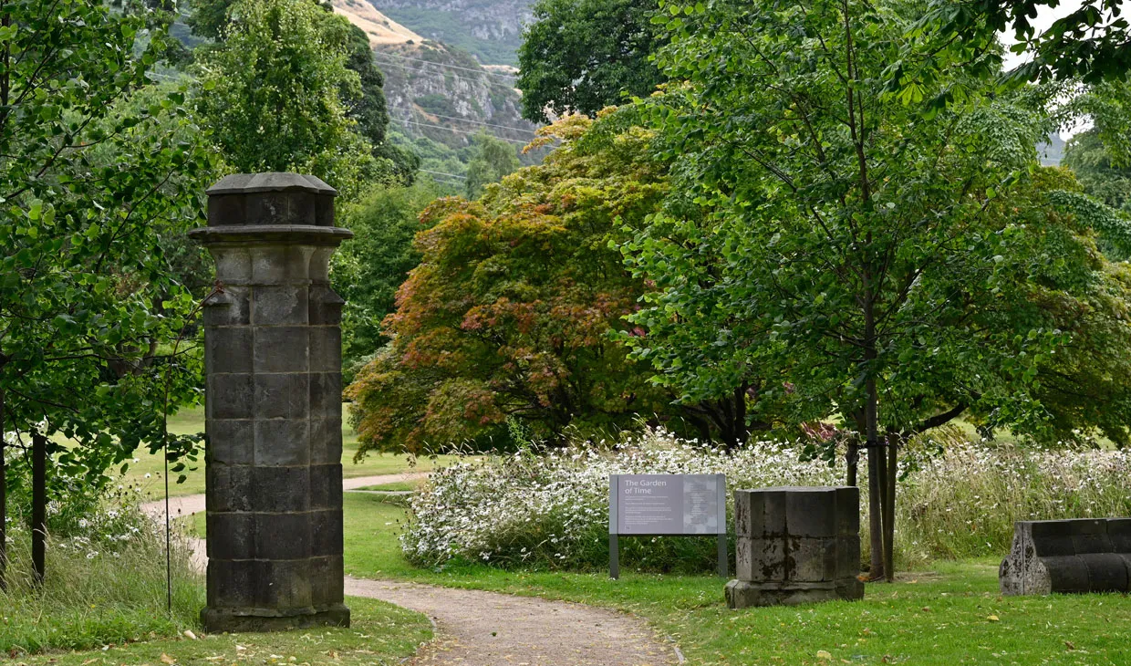 Garden path with sculpture on left hand side and trees on the right.