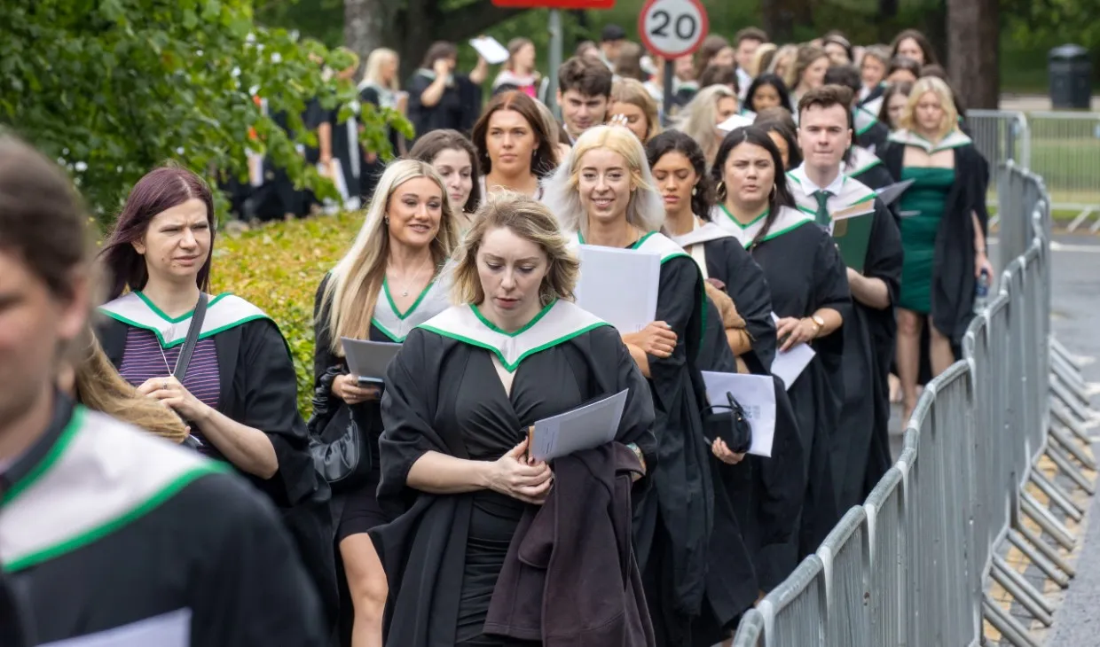 Graduates walking outside the sports centre after graduation