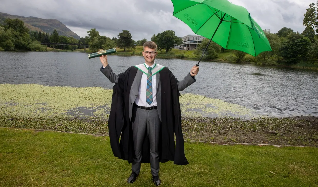 University of Stirling graduate with green umbrella