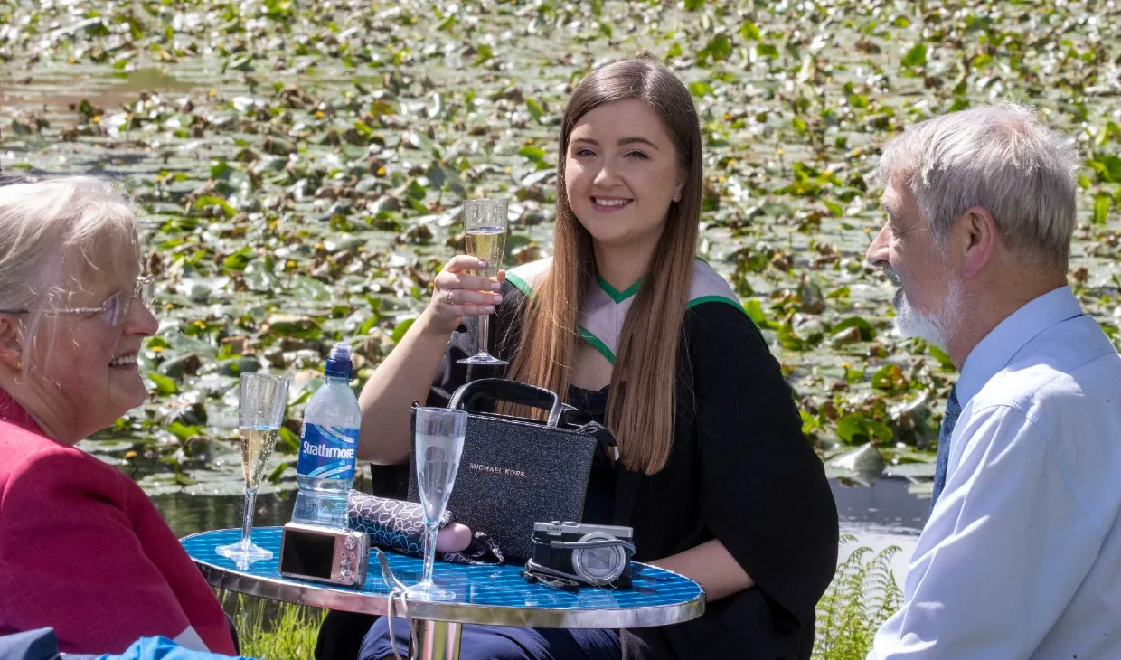 Graduate enjoys a glass of champagne at the graduation garden party