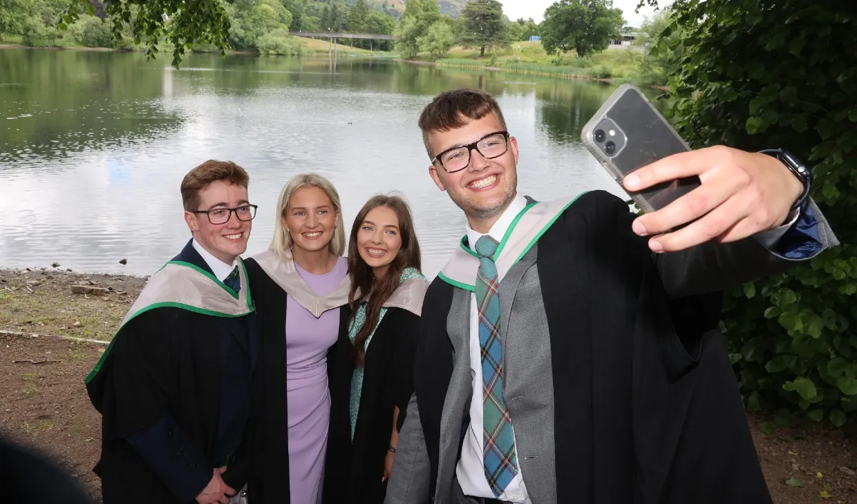 Graduates pose for selfie by the loch