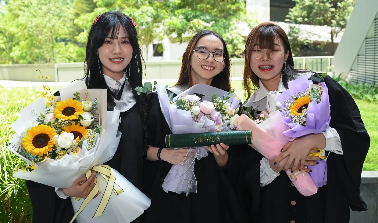 Singapore graduates holding flowers