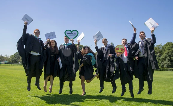 Group of graduates holding signs and jumping