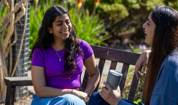 Students sitting on a bench and having a conversation.