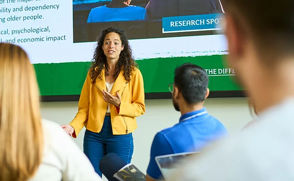 A lecturer addressing a full class of students