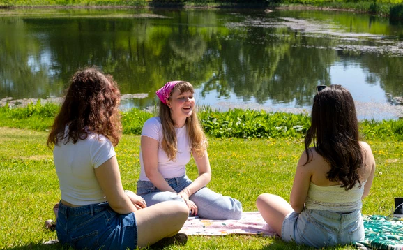 Students sitting by a loch
