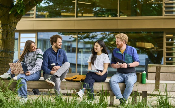 students sitting on bench on campus