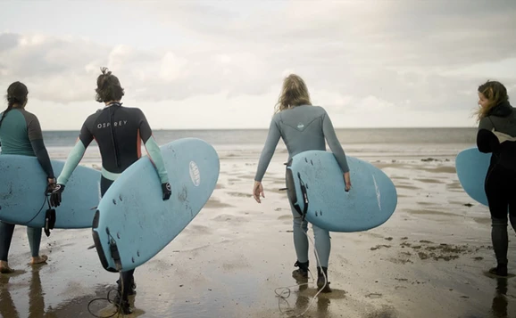 students on beach with surfboards