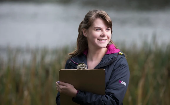 Student holding clipboard by the loch