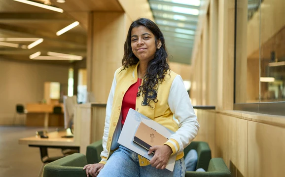 Student holding laptop and notepad