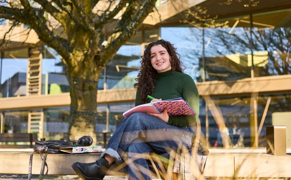 Student sitting on a bench in Queen's Court