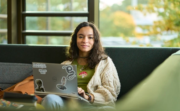 Student sitting in campus central using a laptop