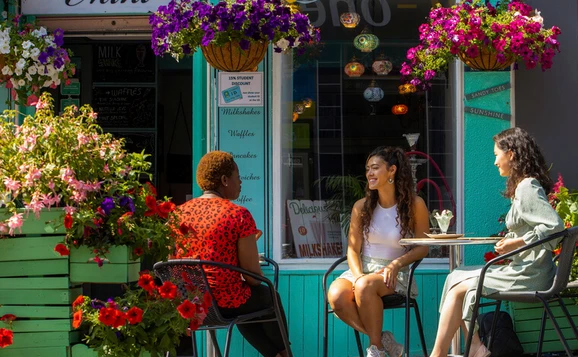 Students sit outside Mint Cafe underneath hanging baskets of flowers