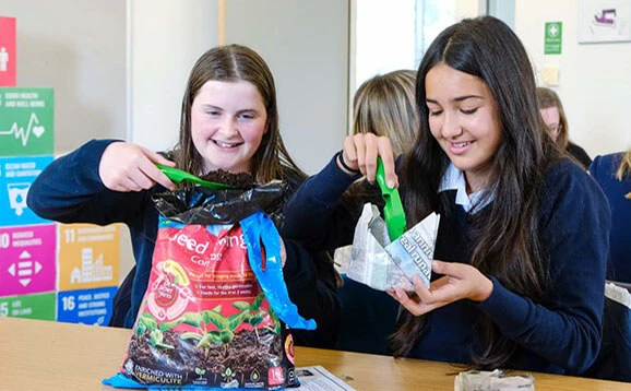 Two school pupils put mud in to paper plant pots at the launch of the Pathfinders initiative