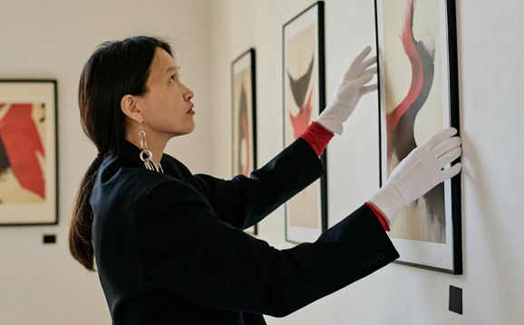 Woman holding artwork with gloves on