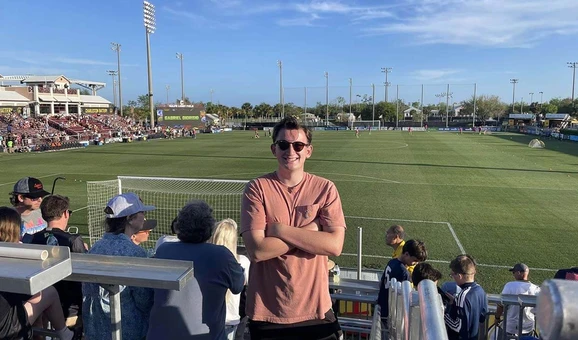 Patrick McBride poses at football sports ground with crowd