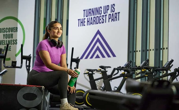 Student holding water bottle in a gym with exercise equipment