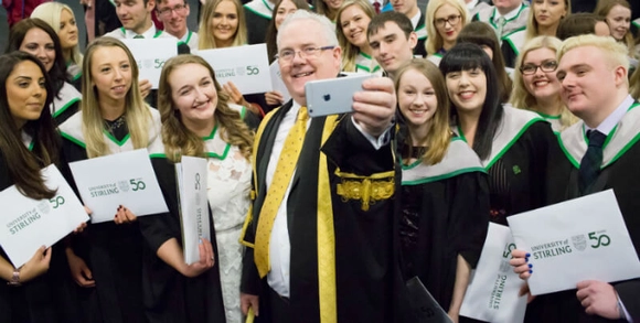 recent graduates with smiles on their faces taking a selfie with stirlings principal