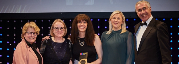 row of women and a man with an award