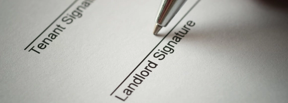 Rental agreement form with signing hand and pen.
