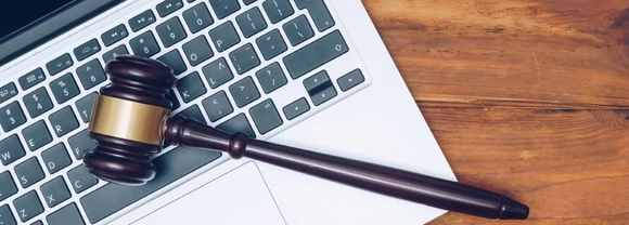 Judge gavel lying on laptop keyboard