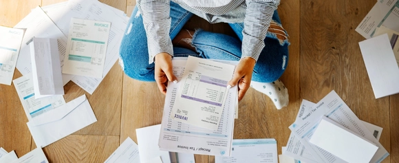 Person sitting on the floor surrounded by bills