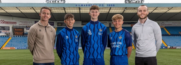 Wellbeing Coaches Bradley Fullarton and Louis Kerr on the pitch at Kilmarnock Football Club with under-18s players Josh, Logan and Charlie