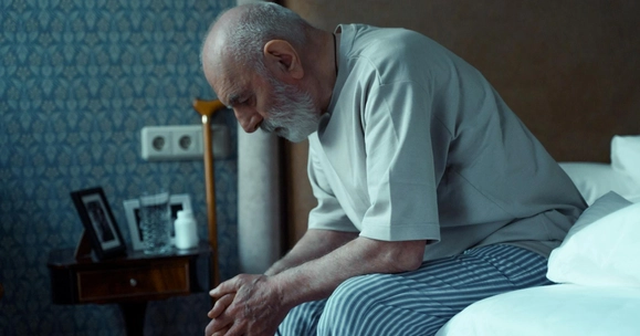 old man sitting on bed