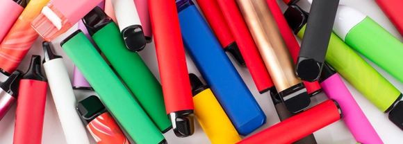 A pile of brightly coloured e-cigarettes scattered across a surface