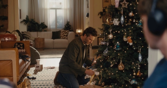 man looking at presents under Christmas tree
