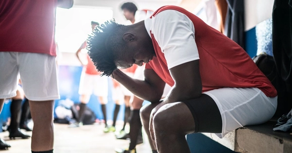 A young footballer looking distressed in the changing room