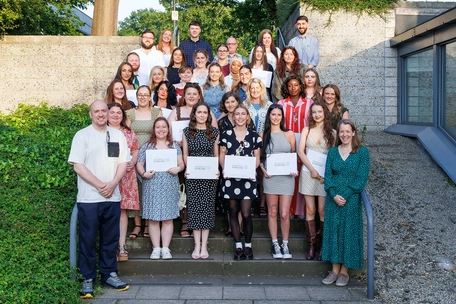 A group of students standing outside holding their course completion certificates