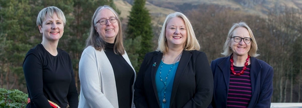 Four women in a row with hills behind