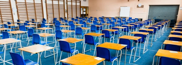 A school hall laid out with blue chairs and single desks