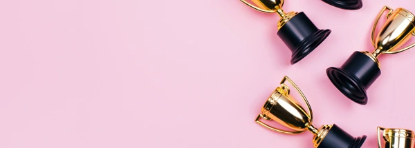 Winner cups on a pink background. Banner with a place for text. Flat lay style.