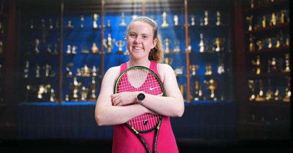Anna McBride poses in front of trophy cabinet at Australian Open 2025.
