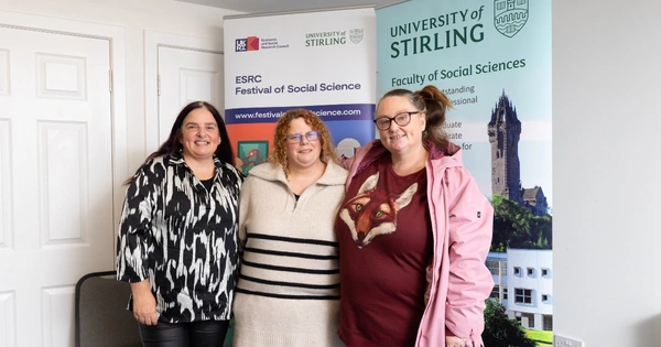 there women smiling in front of banners