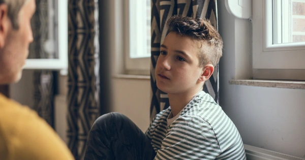 teenage boy sitting at window