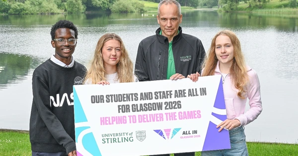 Four people in front of loch holding banner