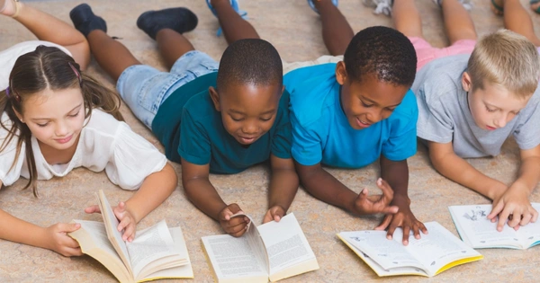 row of children on floor reading books