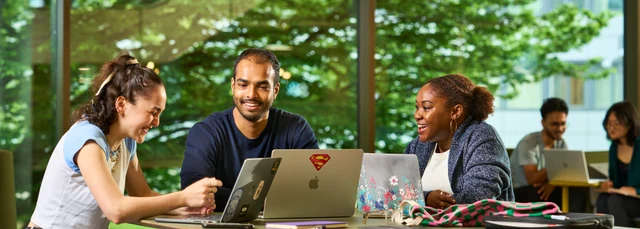 Students sitting with laptops in campus central