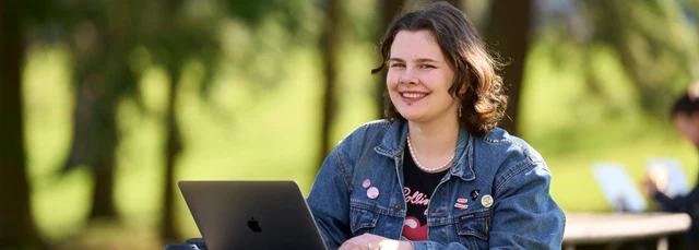 Student sitting outside and using a laptop