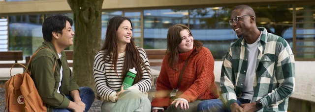 four students sitting outside on campus
