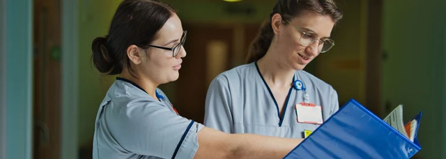 Two student nurses reading a case file