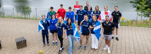 Group of athletes posing with Scottish and other national flags.