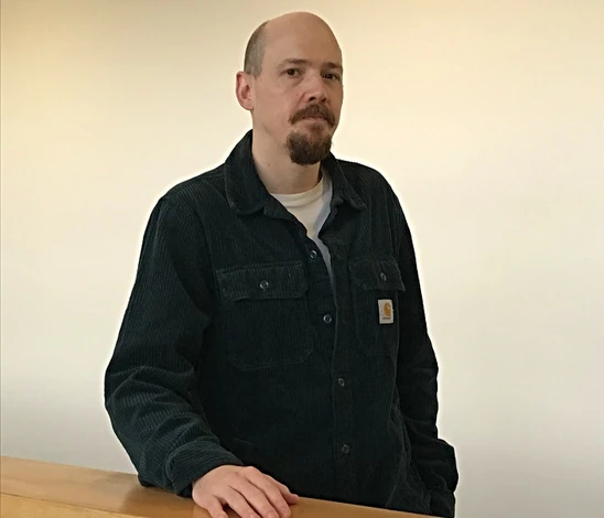 man in black fleece with hand on shelf