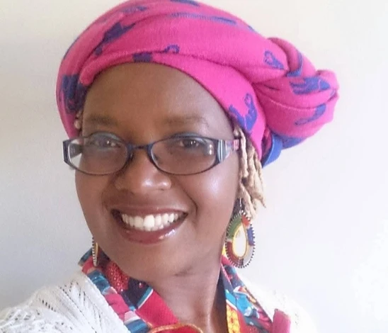 woman with pink headress and glasses smiling