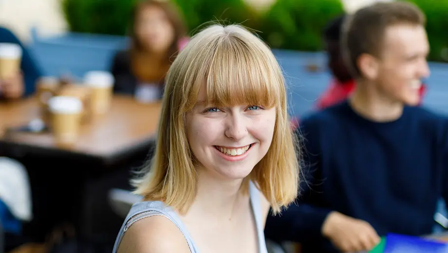 A student sitting in a cafe and smiling